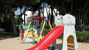 A playground with a red slide, a climbing structure, and a small house-like playhouse. - Holiday apartment near the sea (Lido di Jesolo)