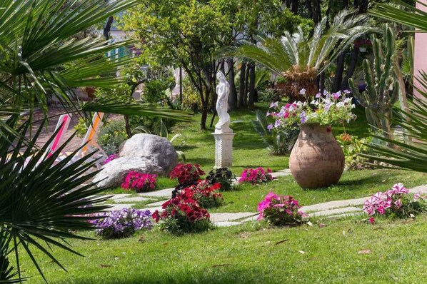 A garden with a statue, large rocks, and flowering plants.