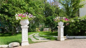Um caminho no jardim com colunas brancas e vasos de flores.