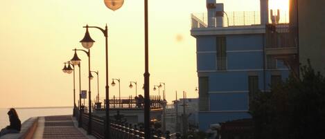 A waterfront promenade with street lamps and a building with balconies.