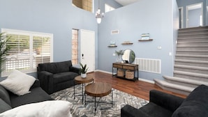 A spacious living room with a high ceiling, a staircase, and a view of the outside. - "Peaceful Avondale Escape – Pool, Hot Tub, Outdoor Living!" (Avondale)