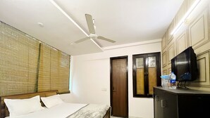 Ein Hotelzimmer mit einem Bett, einem Deckenventilator, einem Fernseher und einer Minibar.