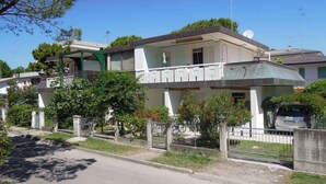 Un edificio residenziale con un balcone, un'antenna parabolica e un cancello.