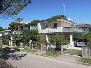 A residential building with a balcony, a satellite dish, and a gated entrance.