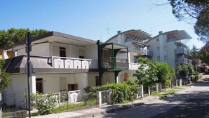 Una strada residenziale con edifici moderni, una struttura con tetto verde e cielo sereno.