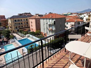 Un quartier résidentiel doté d’une piscine, de balcons et d’immeubles aux toits recouverts de tuiles rouges.