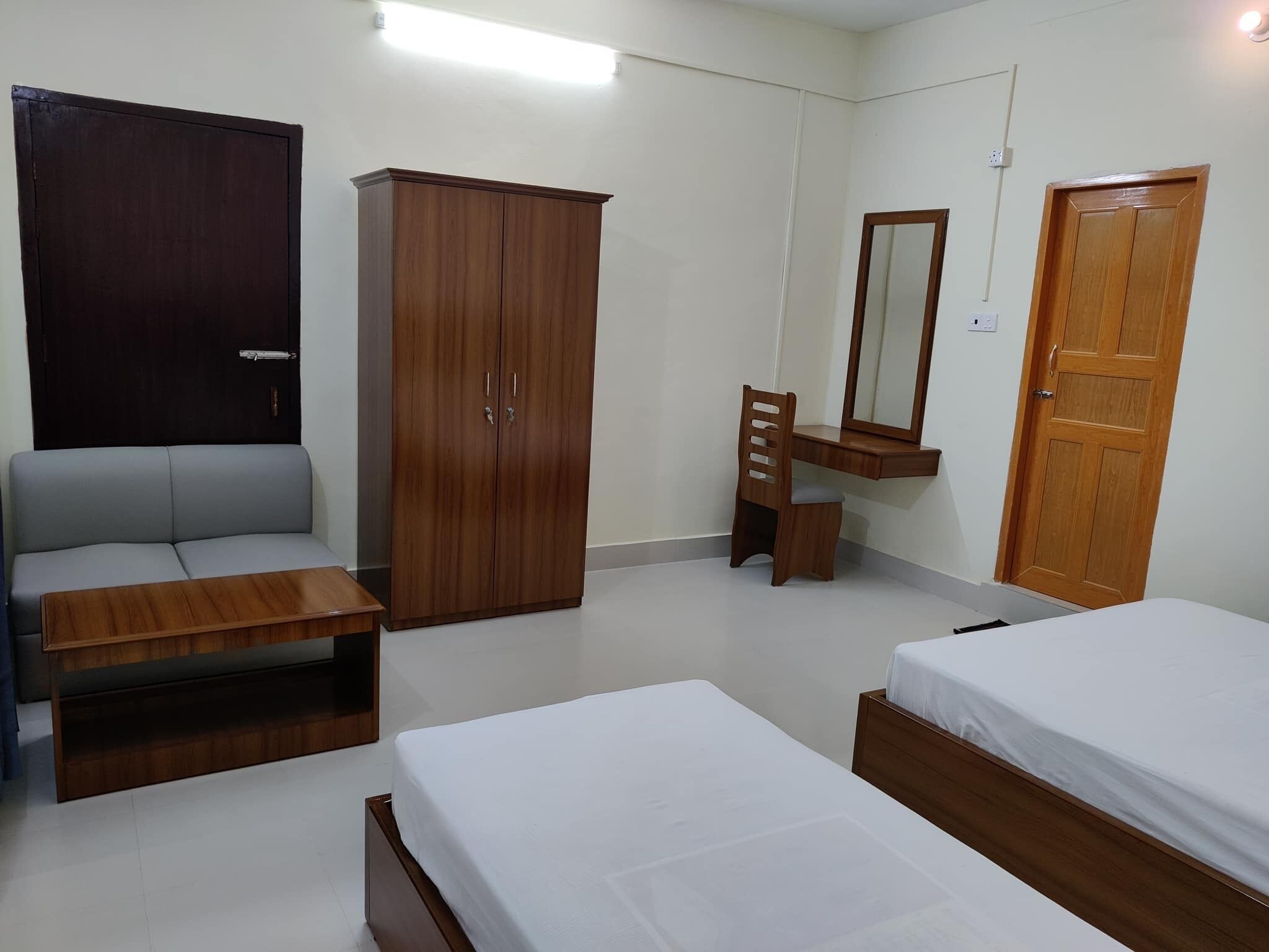 Une chambre avec deux lits, une armoire, un bureau avec un miroir et une chaise.