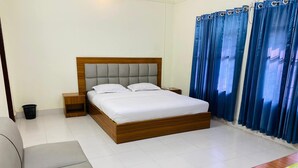 Una camera da letto ordinata con un letto in legno, un comodino in legno, un divano grigio e un tavolo in legno.