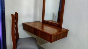 Una stanza d'angolo con una scrivania e una sedia in legno, uno specchio e una tenda blu.