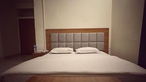Un letto rifatto con ordinata eleganza, con testiera in legno e due cuscini.
