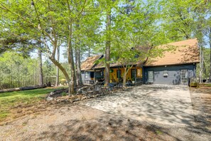 A house with a covered porch, a garage, and a driveway leading to the entrance. - Deck & Hiking Trails: Luxe Georgia Farm Retreat (Lithonia)