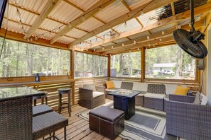 A covered outdoor seating area with wicker furniture, a table, and a fan. - Deck & Hiking Trails: Luxe Georgia Farm Retreat (Lithonia)