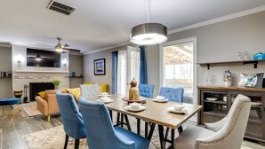A dining area with a wooden table, blue and beige chairs, and a modern pendant light. - Deck & Hiking Trails: Luxe Georgia Farm Retreat (Lithonia)