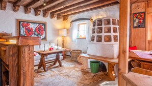 Ein rustikaler Raum mit Holzbalken, einem Kuhfellteppich, einem Holztisch, einer Bank und einer Wand mit einer Zierverkleidung.