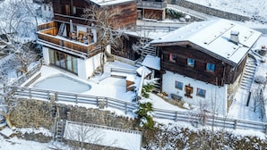 Ein mit Schnee bedecktes Berghotel mit mehreren Holzbauten, einem Schwimmbad und einer Steinschmalseite.