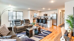 A modern living room with a sofa, a coffee table, and a dining area with chairs. - Modern Elizabeth Apartment ~ 1 Mi to Train Station (Elizabeth)