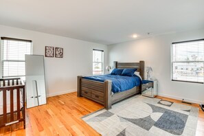 Ein Schlafzimmer mit einem hölzernen Bett, einem Nachttisch, einem Spiegel und einem Babybett.