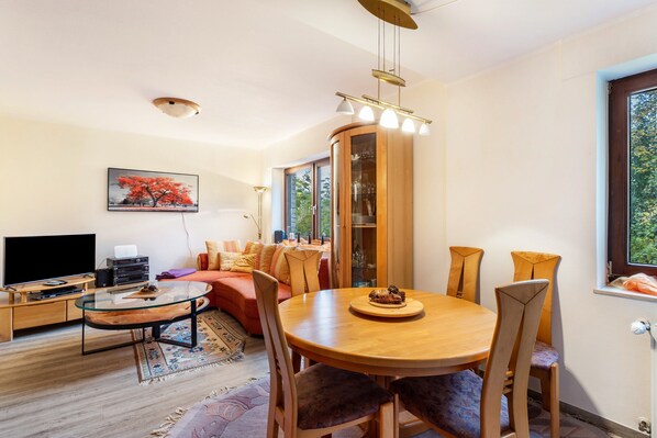 Un salon moderne avec une table basse en verre, une table à manger en bois et des sièges confortables.