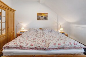 A bedroom with a bed, two bedside tables, a lamp, a wardrobe, and a painting on the wall. - Apartment 'Hof Voege Ferienwohnung 3' with Shared Garden and Wi-Fi (Brodersdorf)
