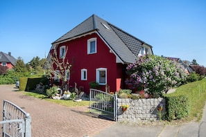 A red house with a stone wall and a metal gate.