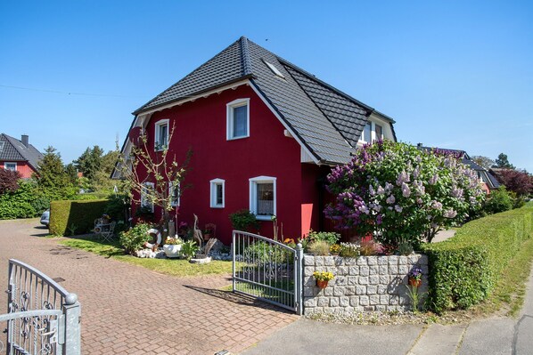 A red house with a stone wall and a metal gate. - Holiday Apartment "Fewo 31 - Halbinsel Darss - Ostsee
" with Private Terrace, Shared Garden & Wi-Fi (Wieck am Darß)