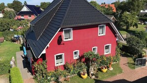 Una casa roja con techo inclinado, antena parabólica y plantas en macetas.