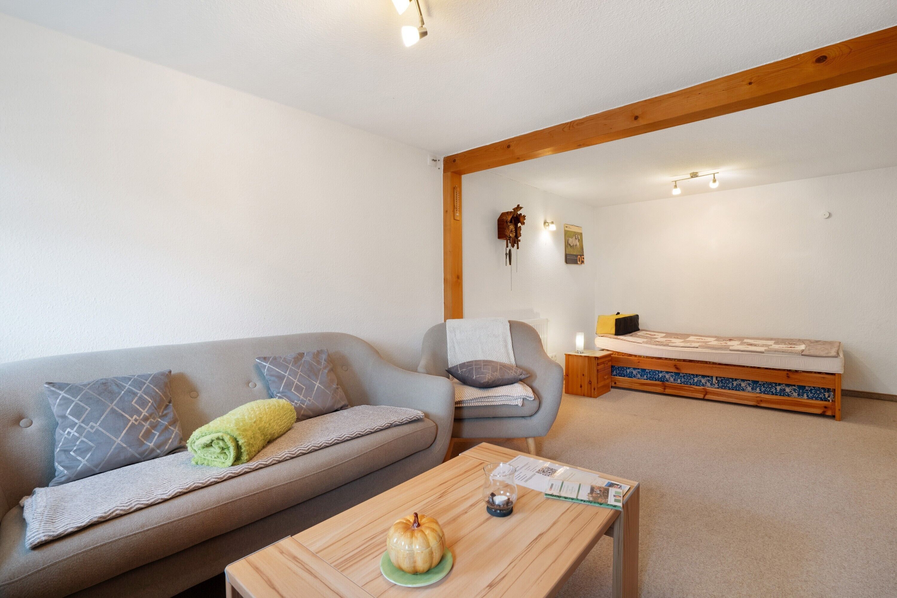 Ein gemütliches Zimmer mit einer Couch, einem Sessel, einem kleinen Tisch und einem Bett.