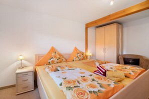 A double bed with floral bedding, a bedside table with a lamp, and a wardrobe.