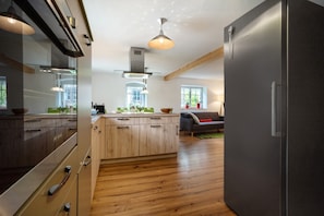 A modern kitchen with wooden cabinets, a built-in oven, and a large island with a sink.