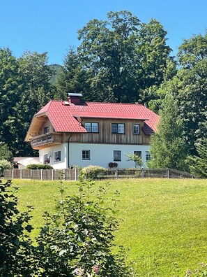 Ein zweistöckiges Haus mit rotem Dach, Holzfassade und einem Balkon.
