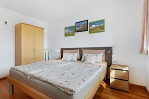 A bedroom with a bed, a wardrobe, a bedside table, and three framed pictures on the wall. - Apartment 'Haus Rosenheim' with Mountain View, Balcony and Wi-Fi (Ramsau am Dachstein)