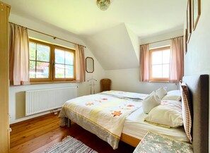 A bedroom with a bed, a radiator, a window, and a door.