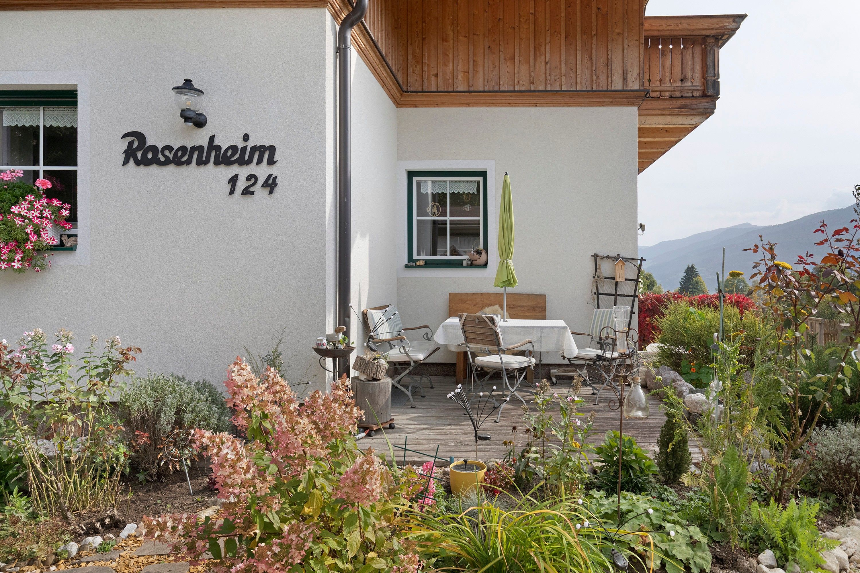 Une maison avec une plaque indiquant « Rosenheim 124 » et une terrasse aménagée avec du mobilier d’extérieur.