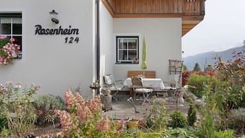Une maison avec une plaque indiquant « Rosenheim 124 » et une terrasse aménagée avec du mobilier d’extérieur.