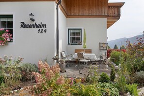 Een huis met een bord waarop 'Rosenheim 124' staat en een terras met tuinmeubilair.