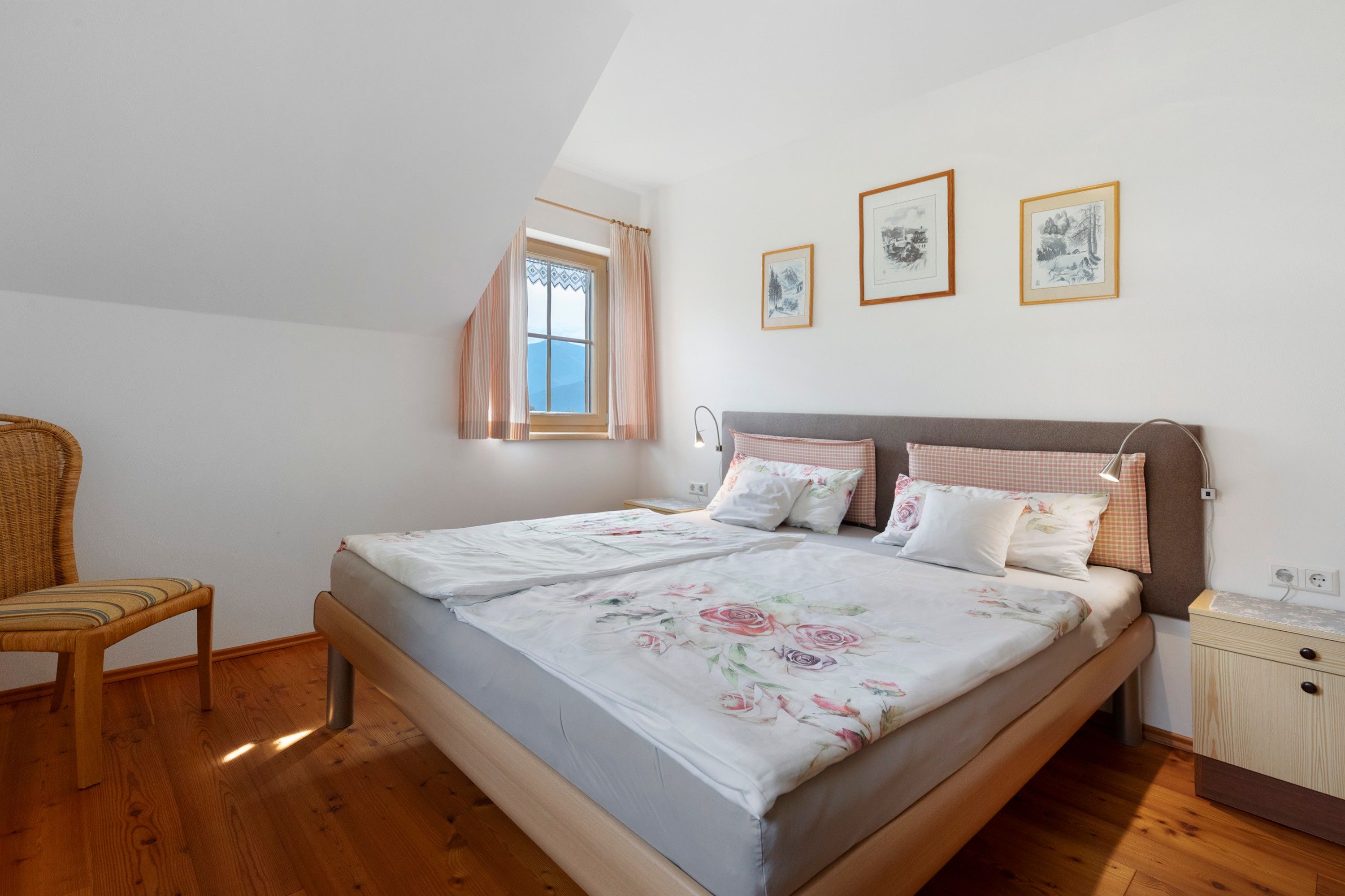 Een slaapkamer met een bed, een stoel, een raam en kunst aan de muur.
