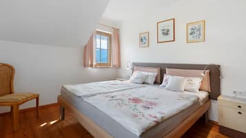 Een slaapkamer met een bed, een stoel, een raam en kunst aan de muur.