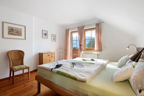 A bedroom with a bed, a chair, a dresser, and a window with curtains.