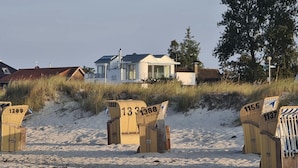 Beach chairs numbered 1289, 1333, 1388, 1355, and 137 on a sandy beach with a house in the background. - Apartment 'Ferienwohnung Backbord' with Sea View, Shared Garden and Wi-Fi (Schönberg-Kalifornien)