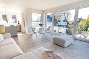 Un apartamento moderno con comedor, sofá y ventanas amplias que dan al vecindario.