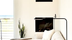 A modern living room with a large window, a sofa, a plant, and a flat-screen TV mounted on the wall. - Apartment 'Ferienwohnung Backbord' with Sea View, Shared Garden and Wi-Fi (Schönberg-Kalifornien)