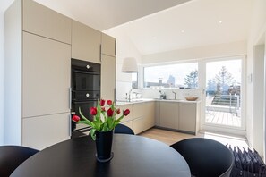 A modern kitchen with a dining area, a view of the city, and a balcony.