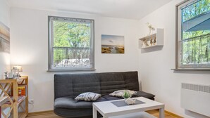 A modern living room with a grey sofa, white coffee table, and a bookshelf.