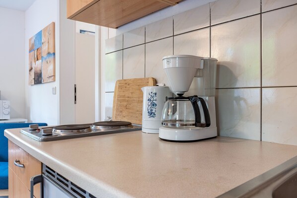 A kitchen with a coffee maker, a cutting board, and a microwave.