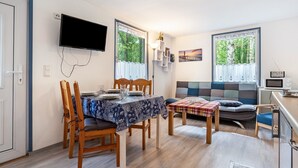 A dining area with a table set for four, a sofa, and a television mounted on the wall.