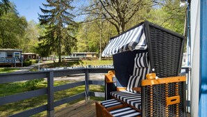 Una terrazza in legno con un letto dotato di tenda a righe e un piccolo tavolino.