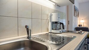 A modern kitchen with a stainless steel sink, a coffee maker, and a microwave. - Bungalow 'Bungalow Kay, Bgl  4' with Private Terrace and Wi-Fi (Dranske)