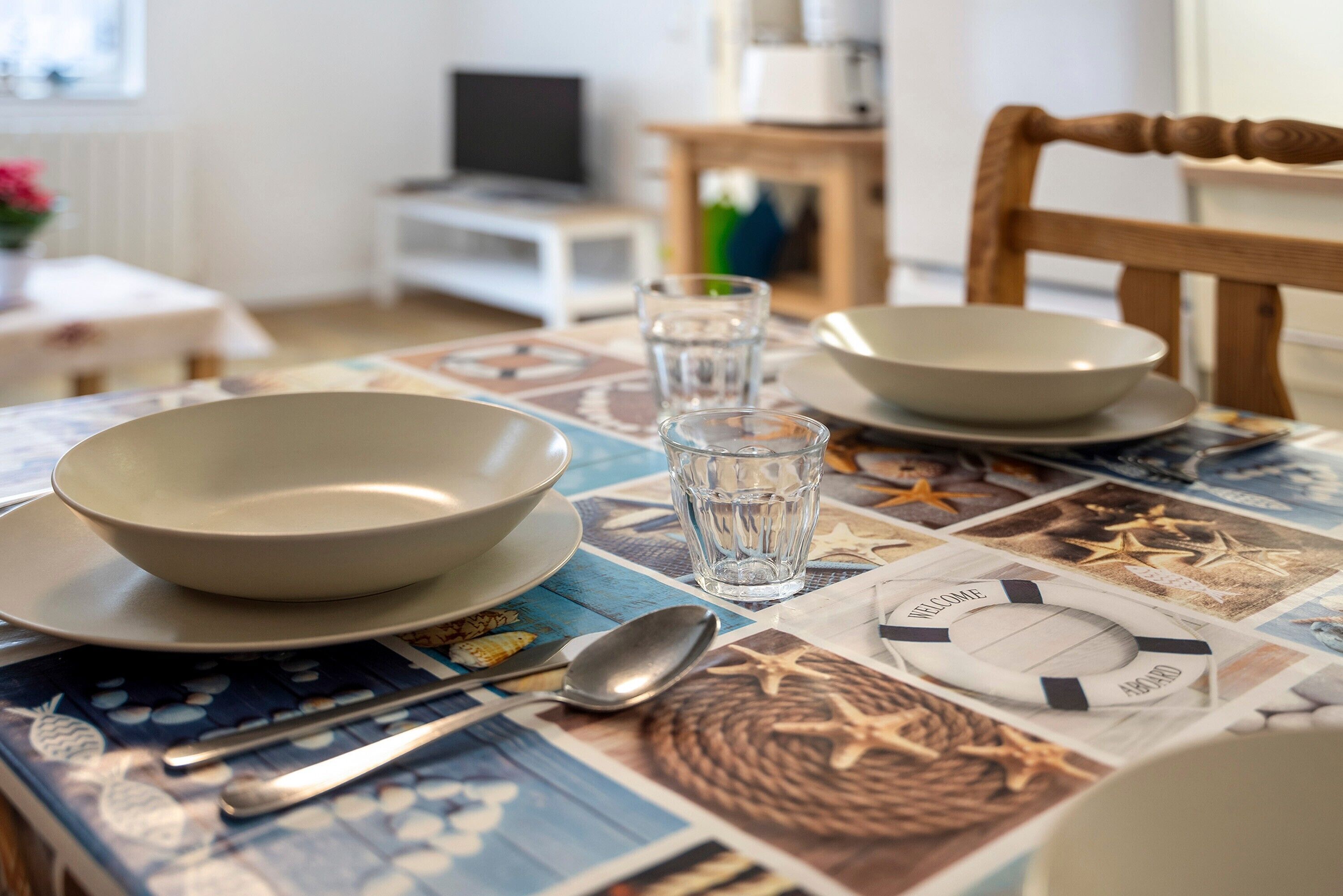 Une table à manger avec des assiettes, des bols, un verre d’eau et des couverts.