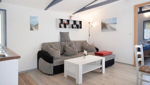 Una sala de estar moderna con un sofá, una mesa de centro blanca y un pequeño estante con adornos.