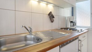 Una cocina moderna con un lavamanos de acero inoxidable, una encimera de madera y una cafetera.